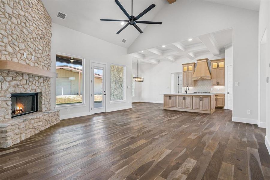 Unfurnished living room featuring beamed ceiling, a fireplace, a ceiling fan, dark wood-type flooring, and high vaulted ceiling