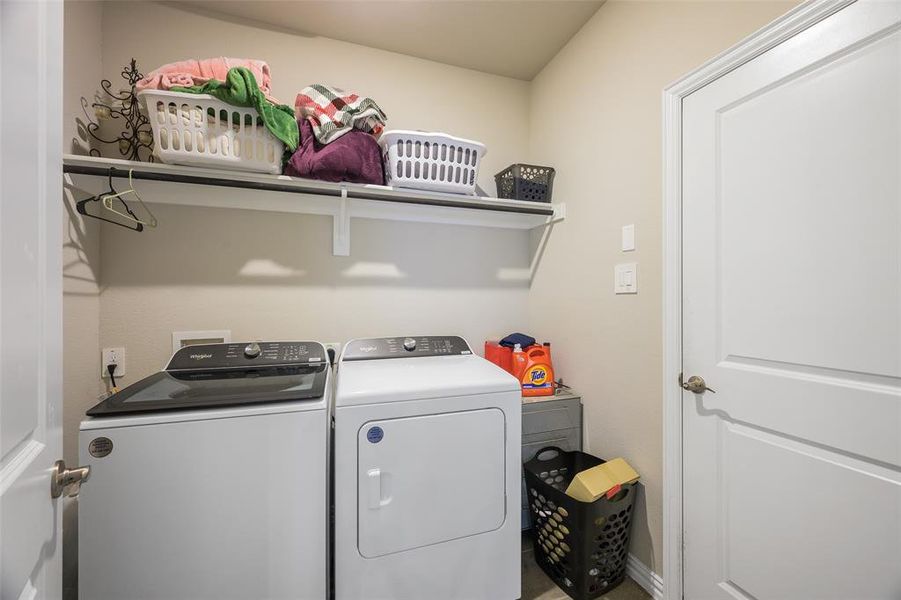 Dedicated laundry area featuring a white shelving unit, light neutral wall paint, and white trim Dedicated laundry area featuring a white shelving unit, light neutral wall paint, and white trim
