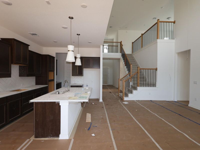 An open-concept living space presents a modern kitchen island and a grand staircase.