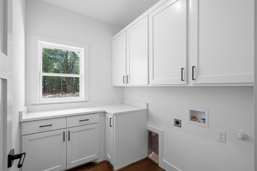 Laundry area featuring dark wood finished floors, cabinet space, washer hookup, and hookup for an electric dryer Laundry area featuring dark wood finished floors, cabinet space, washer hookup, and hookup for an electric dryer