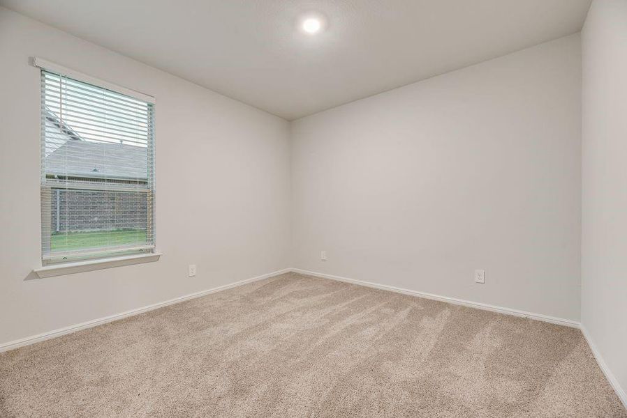 Neutral-toned carpeted room featuring a single window with horizontal blinds and a recessed ceiling light