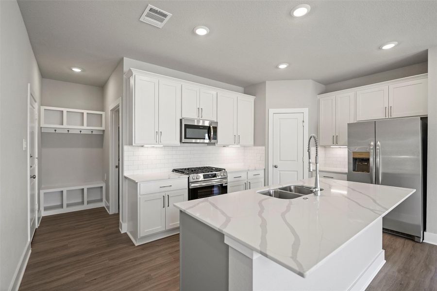 Gorgeous chef’s kitchen with gleaming counters, ample cabinetry, and stainless steel appliances.