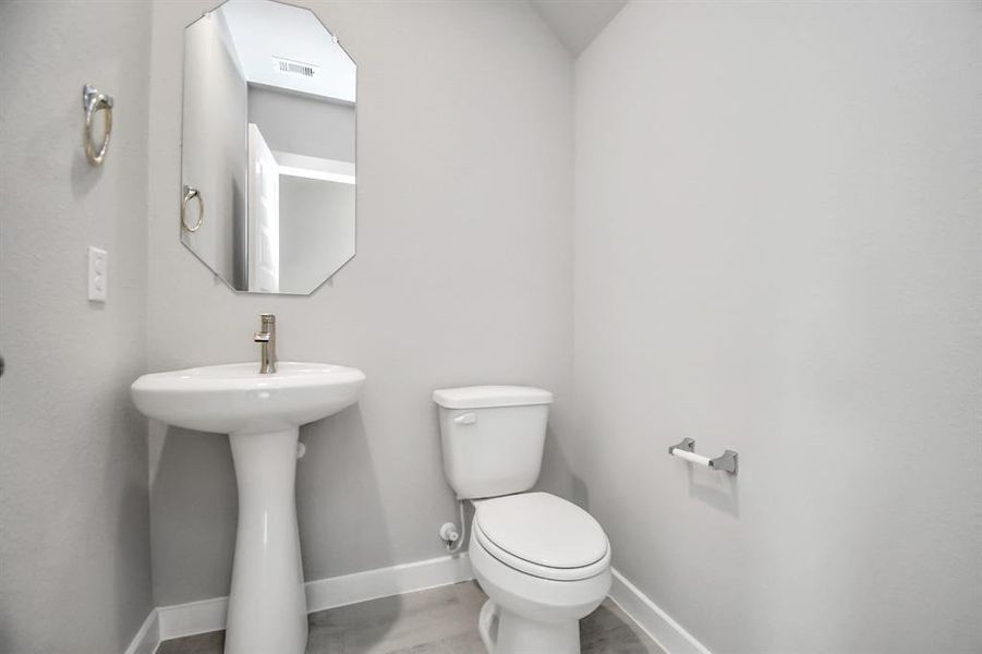 Step into this bright and airy half bath, where a sleek pedestal sink and modern hardware elevate the space with contemporary charm.