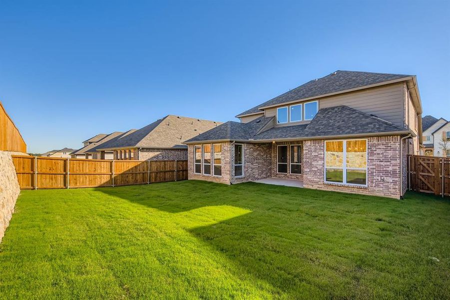Rear view of house with a patio, brick siding, roof with shingles, and a fenced backyard