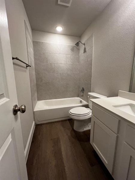 Full bathroom featuring hardwood / wood-style flooring, vanity, toilet, and tiled shower / bath