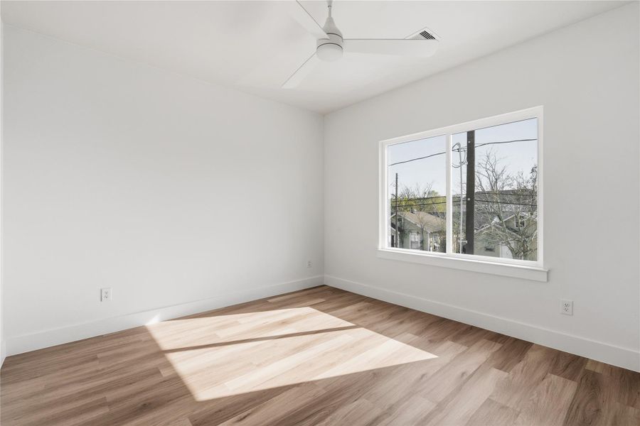 Large windows bring in consistent natural light, making this guest bedroom feel open and comfortable throughout the day.