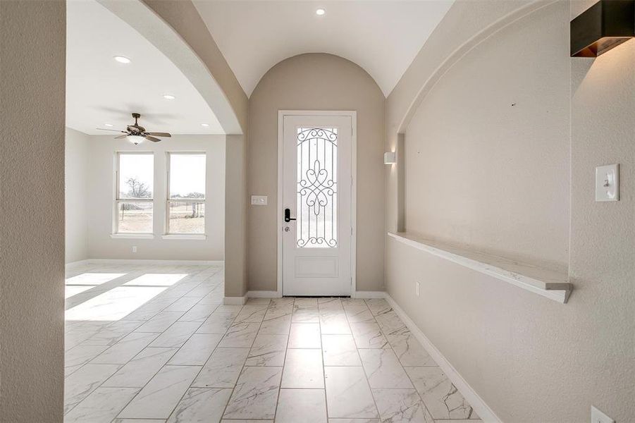 Foyer entrance featuring ceiling fan and lofted ceiling