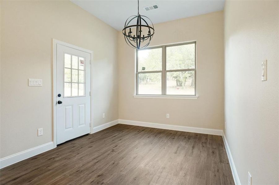 Unfurnished dining area with dark hardwood / wood-style floors and a notable chandelier