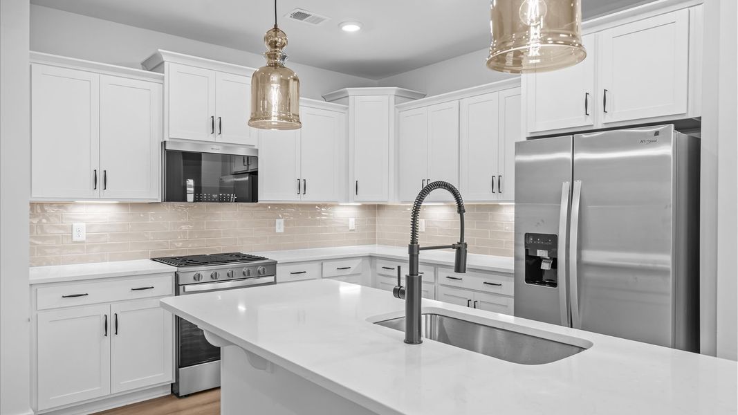 Highly skilled kitchen design includes a 9-foot island, quartz countertops, and stylish pendant fixtures in Anderson, SC
