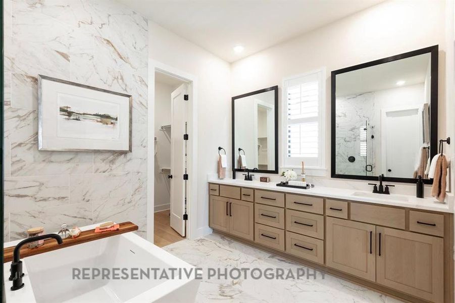 Bathroom featuring light marble finish floors, double vanity, a marble finish shower, a soaking tub, and tile walls Bathroom featuring light marble finish floors, double vanity, a marble finish shower, a soaking tub, and tile walls
