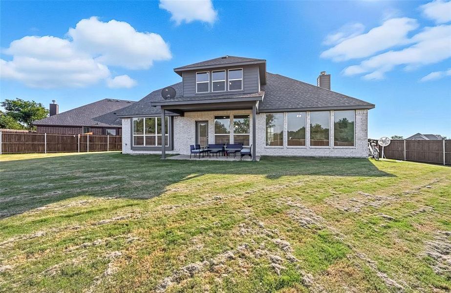 Back of property with brick siding, a patio area, a fenced backyard, a chimney, and a shingled roof
