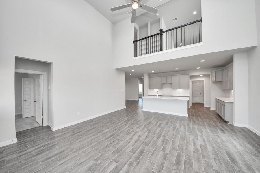 Relax and unwind in this inviting family room, illuminated by abundant natural light streaming in through tall windows, complemented by high ceilings and stunning flooring. Stay comfortable year-round with the gentle breeze from the ceiling fan, creating the perfect atmosphere for family gatherings.