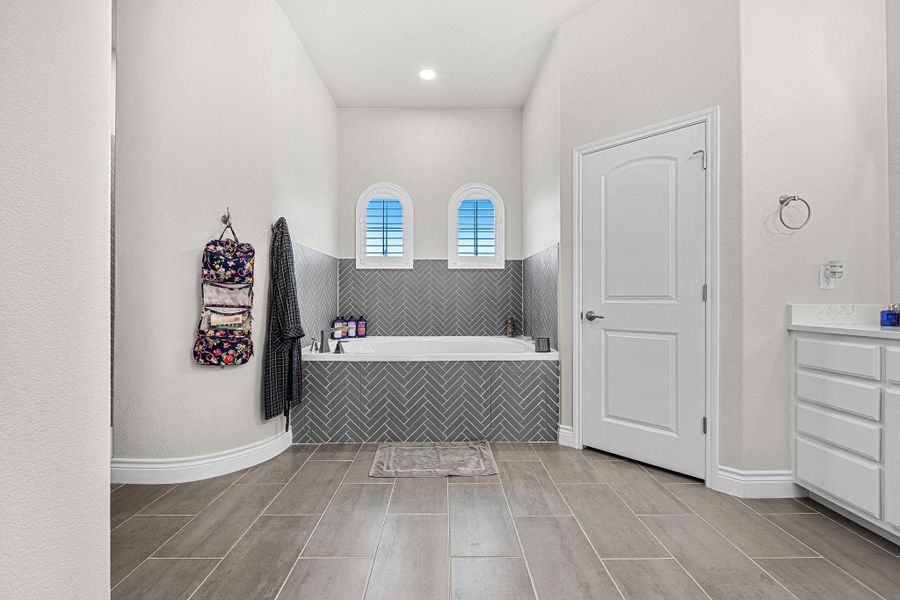 Indulge in relaxation within this primary bathroom featuring an inviting soaking tub and spacious tile flooring. Indulge in relaxation within this primary bathroom featuring an inviting soaking tub and spacious tile flooring.