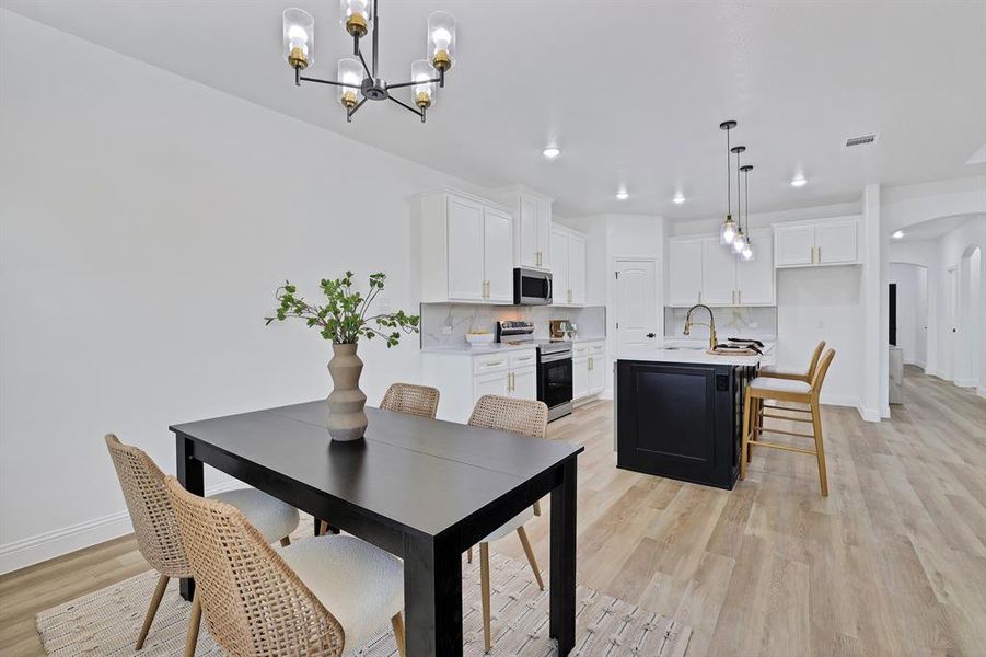 Dining space featuring sink, a notable chandelier, and light wood-type flooring