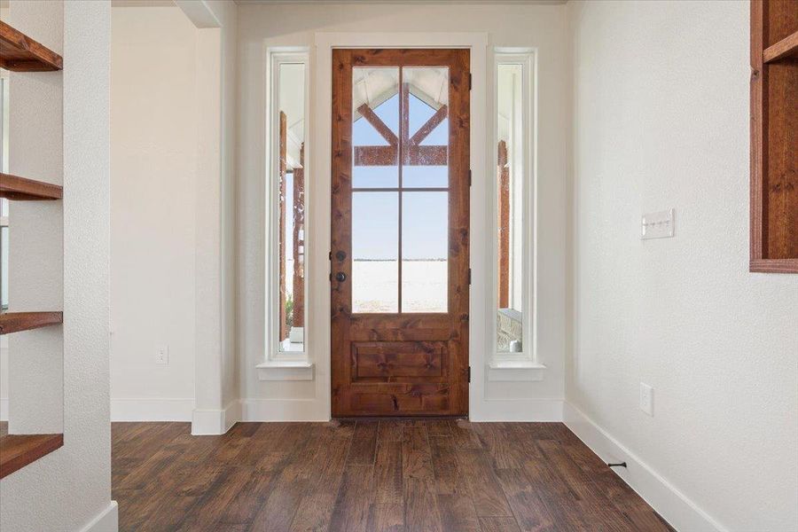 A welcoming wooden front door with glass panels and sidelights opens to reveal expansive outdoor views.