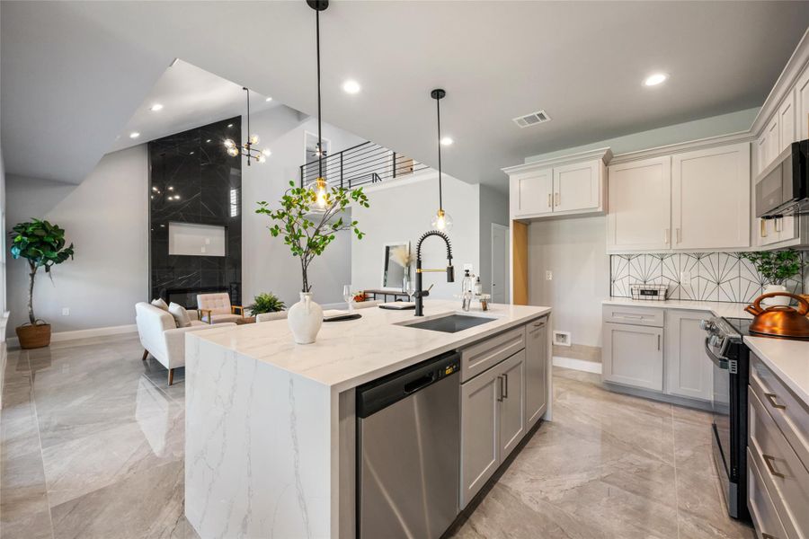 Kitchen with appliances with stainless steel finishes, light marble finish flooring, decorative light fixtures, open floor plan, and recessed lighting