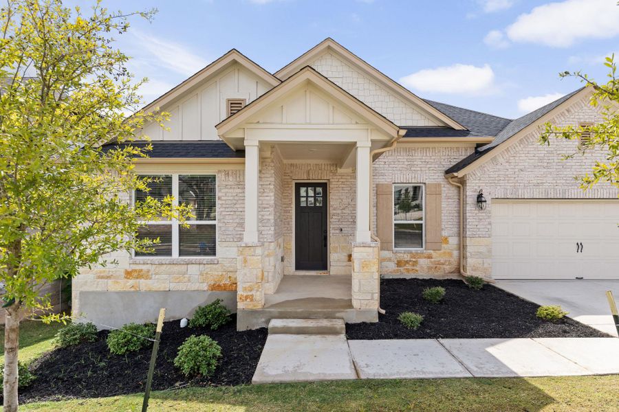 Craftsman-style house with board and batten siding, an attached garage, brick siding, and roof with shingles