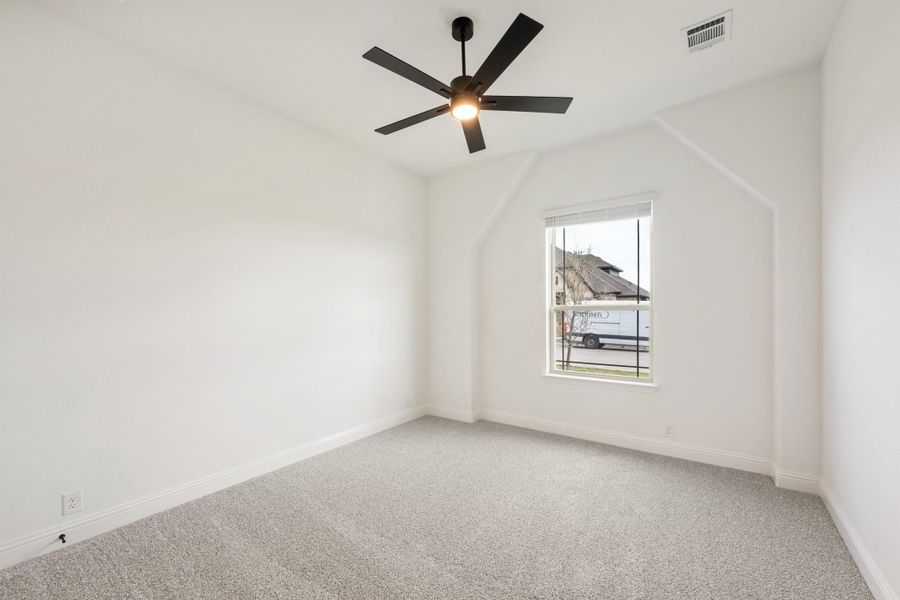 Empty bedroom with gray carpet, white walls, black ceiling fan, and single window