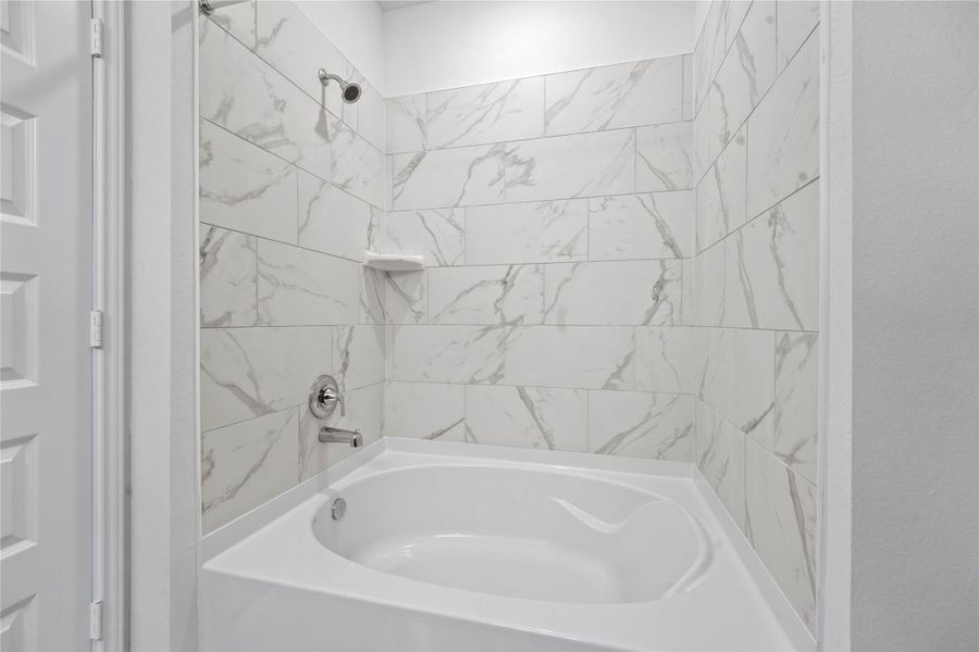 This view highlights the primary bathroom's versatile tub/shower combination, thoughtfully designed to accommodate both a quick, invigorating morning shower and a luxurious, deep soak after a long day.