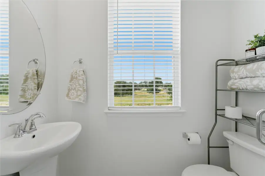 A window in this powder room offers a view of green fields, enhancing the bright, minimalist space. A window in this powder room offers a view of green fields, enhancing the bright, minimalist space.