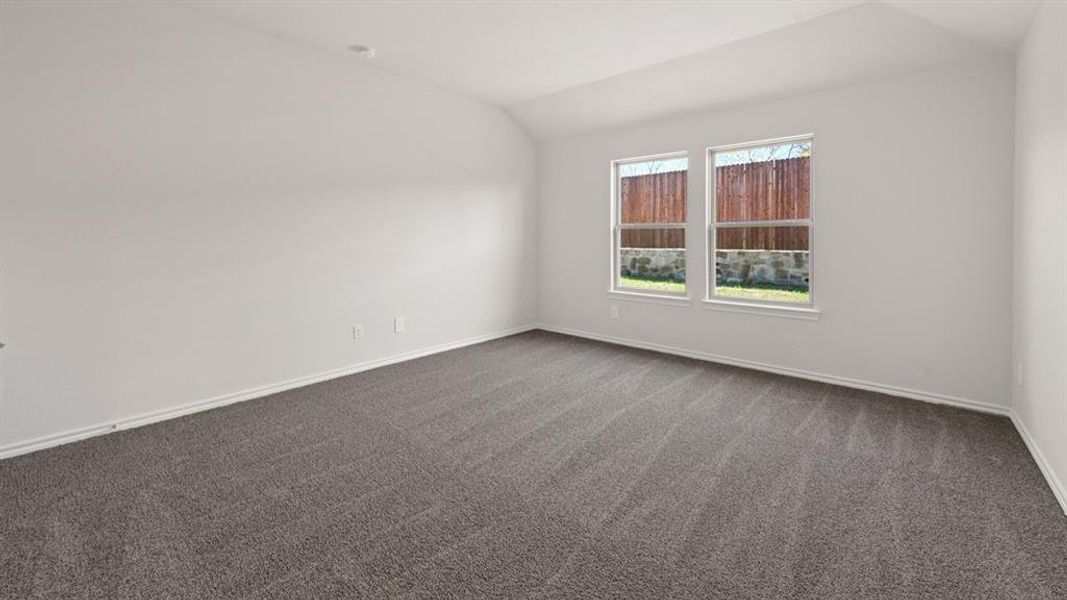 Spacious room featuring neutral carpeting, white walls, two large windows, white trim, and a vaulted ceiling