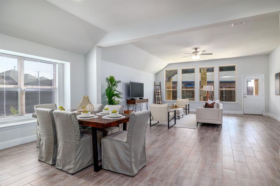 Dining space with lofted ceiling, wood finished floors, and ceiling fan