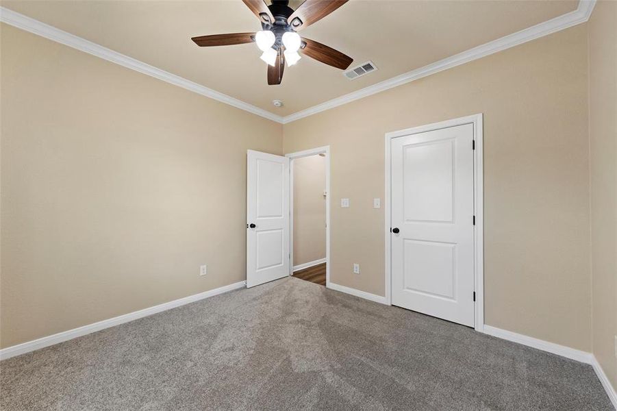 Unfurnished bedroom featuring crown molding, carpet flooring, and a ceiling fan