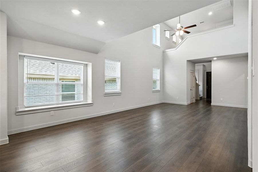 Empty room with a ceiling fan, dark wood-type flooring, recessed lighting, and vaulted ceiling Empty room with a ceiling fan, dark wood-type flooring, recessed lighting, and vaulted ceiling