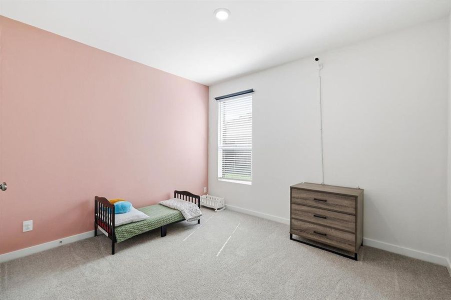 Spacious room featuring light-colored carpet, a large window with blinds, and a recessed ceiling light fixture Spacious room featuring light-colored carpet, a large window with blinds, and a recessed ceiling light fixture