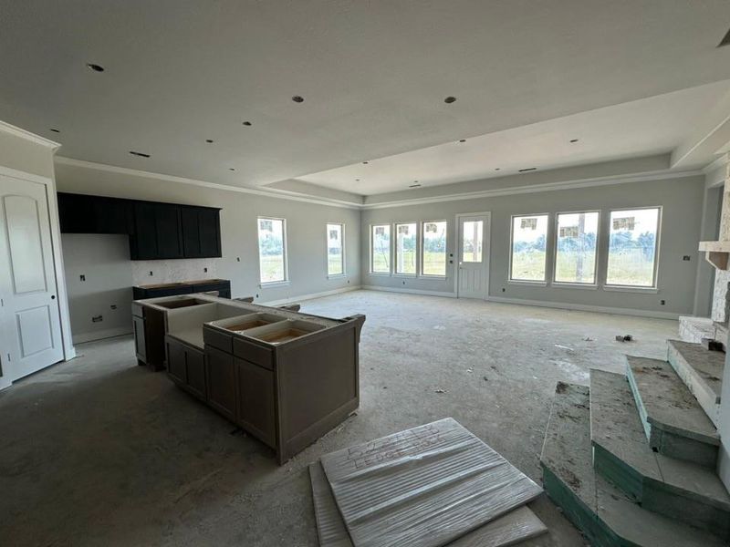 Open-concept living space featuring a tray ceiling, recessed lighting, crown molding, and multiple large windows