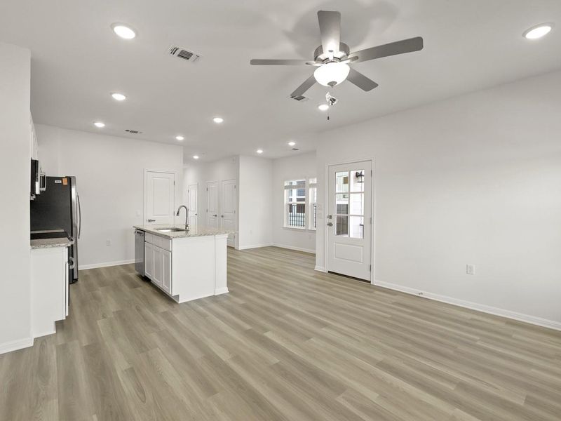 A contemporary kitchen and living area showcases a practical island with a sink and abundant natural light.