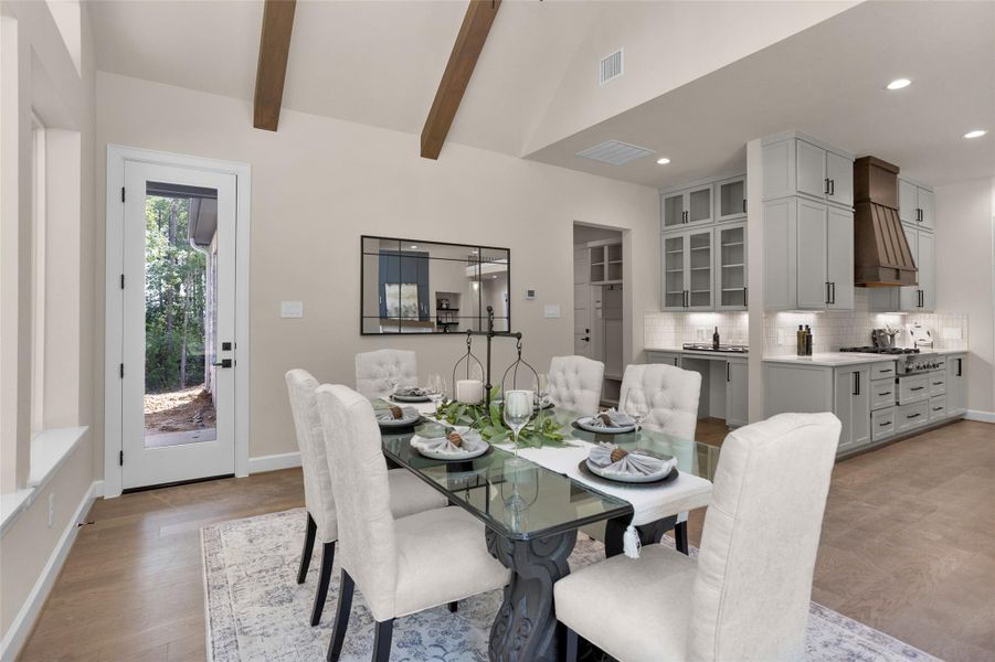 This view highlights the open flow between the dining area and kitchen, where a built-in serving area doubles as a butler’s pantry with glass-front cabinets, under-cabinet lighting and extra counter space.