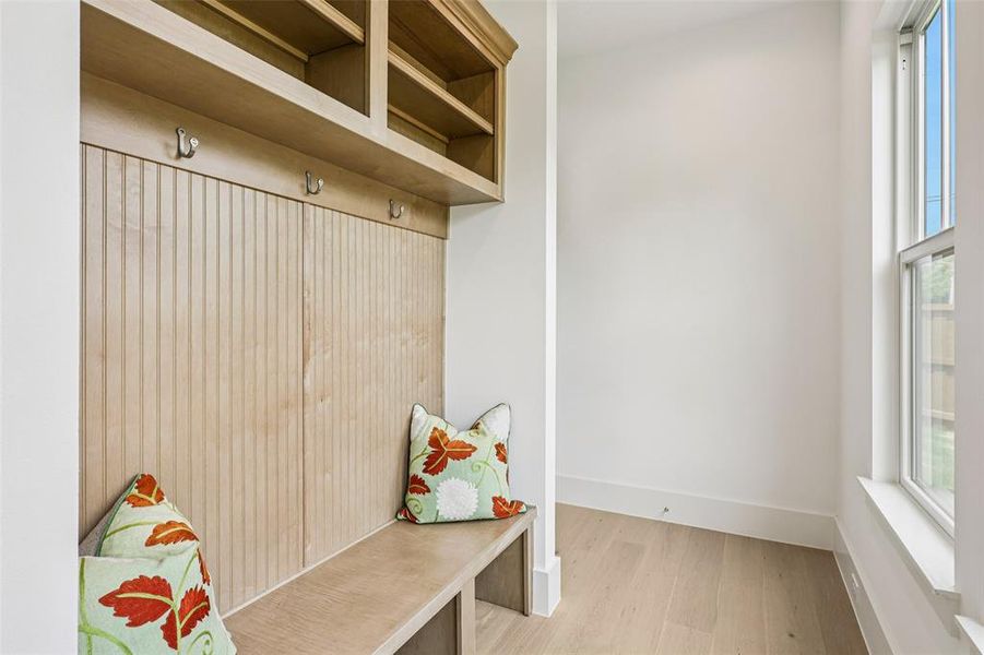 Built-in custom wood mudroom bench with storage cubbies and upper shelving