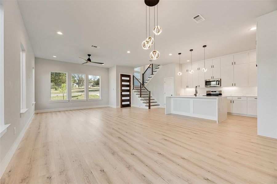 Unfurnished living room featuring stairs, recessed lighting, light wood-type flooring, and a ceiling fan Unfurnished living room featuring stairs, recessed lighting, light wood-type flooring, and a ceiling fan