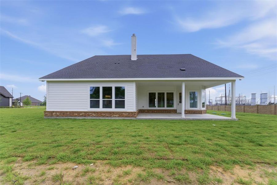 The property features a spacious yard with a covered patio, multiple windows, and a brick and siding exterior