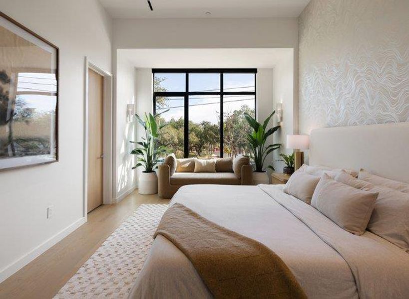 Bedroom featuring a large window with black framing, providing abundant natural light