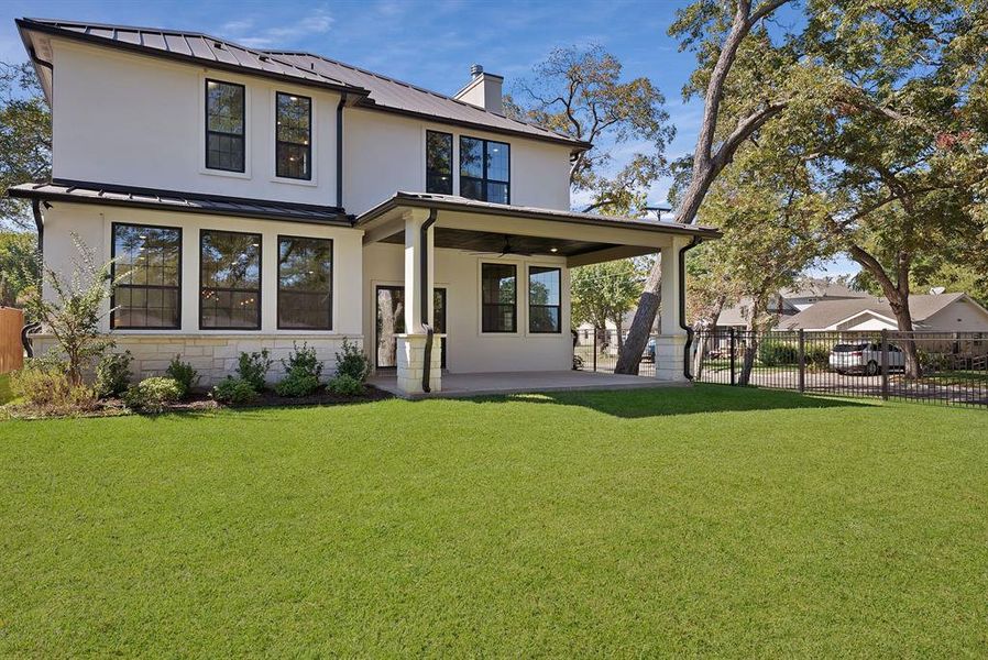 Back of house featuring a metal roof, a patio, a chimney, a standing seam roof, and stucco siding Back of house featuring a metal roof, a patio, a chimney, a standing seam roof, and stucco siding