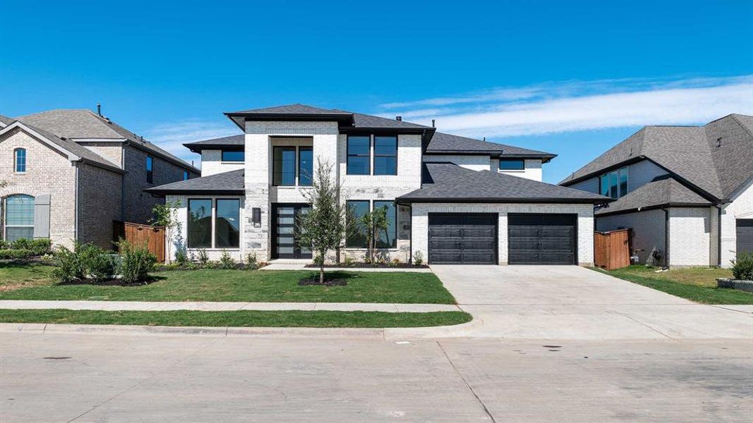 View of front of house featuring a front lawn and a garage