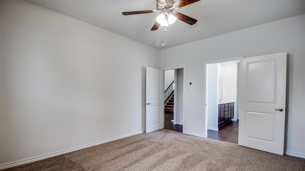 Unfurnished bedroom with dark carpet, ensuite bath, and ceiling fan Unfurnished bedroom with dark carpet, ensuite bath, and ceiling fan