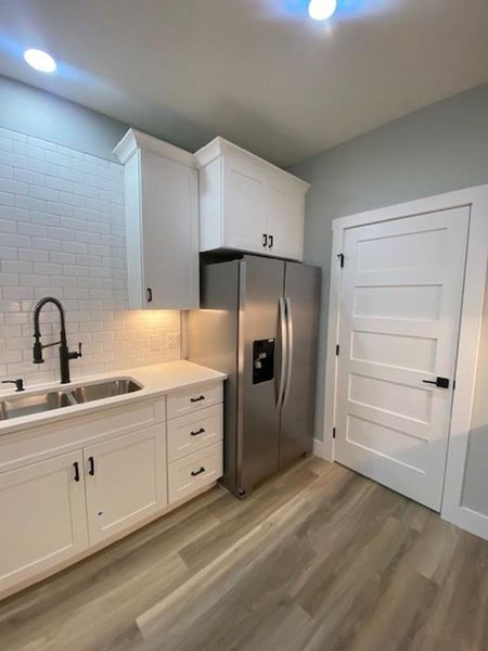 A sleek kitchen features modern white cabinetry, stainless steel appliances, and durable flooring. A sleek kitchen features modern white cabinetry, stainless steel appliances, and durable flooring.