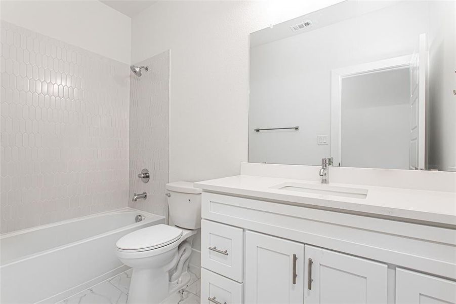 Full bathroom featuring tiled shower / bath combo, toilet, and vanity