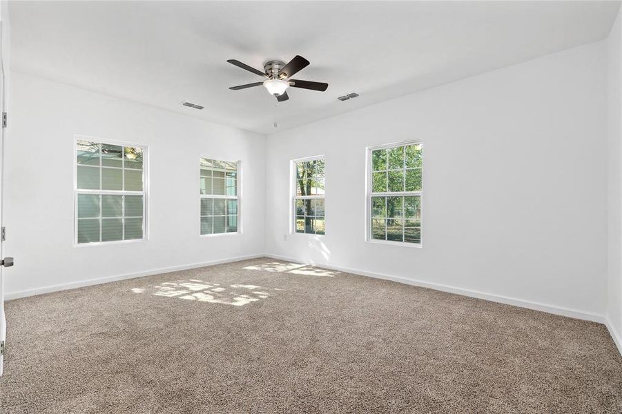 Empty room featuring carpet floors and a ceiling fan Empty room featuring carpet floors and a ceiling fan