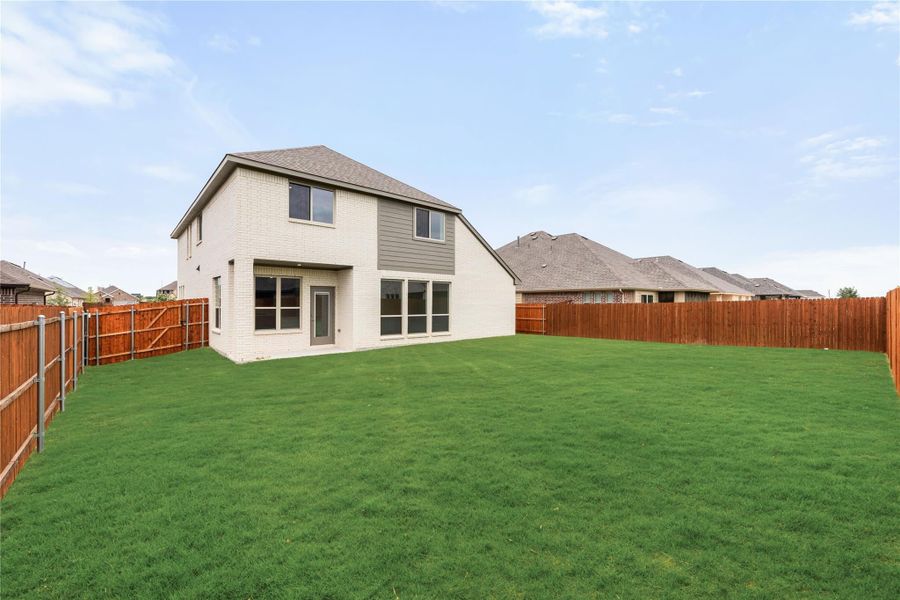 Two-story white brick home with large grassy backyard enclosed by wood privacy fence Two-story white brick home with large grassy backyard enclosed by wood privacy fence