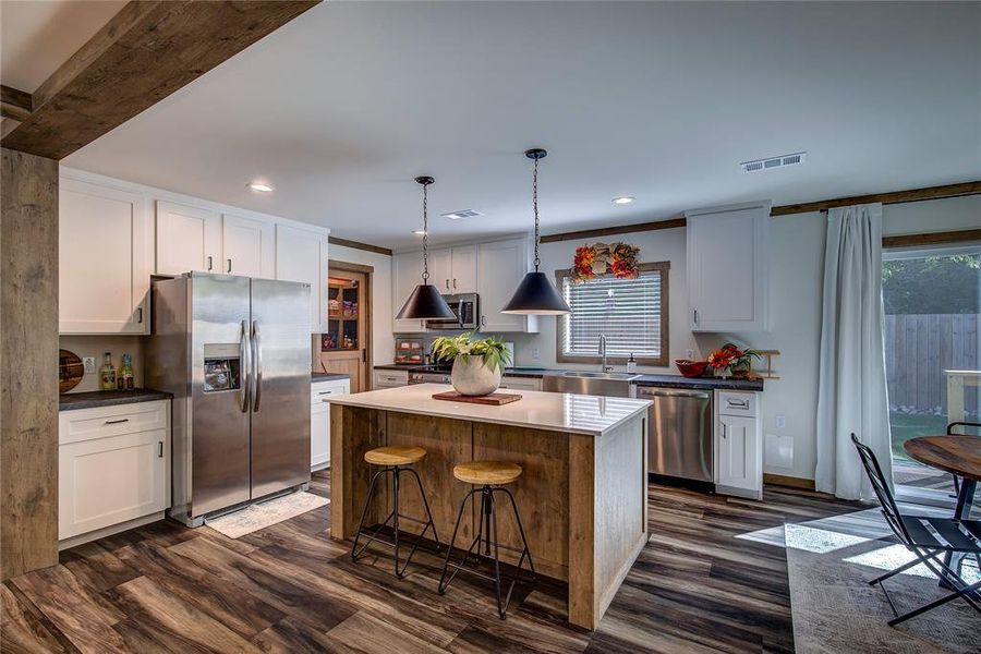 Kitchen featuring stainless steel appliances, a kitchen island, pendant lighting, LVP floors, and recessed lighting