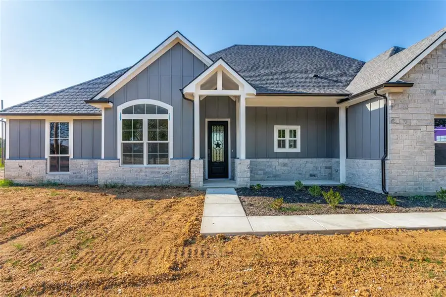 Craftsman-style house featuring board and batten siding, covered porch, a shingled roof, and stone siding Craftsman-style house featuring board and batten siding, covered porch, a shingled roof, and stone siding