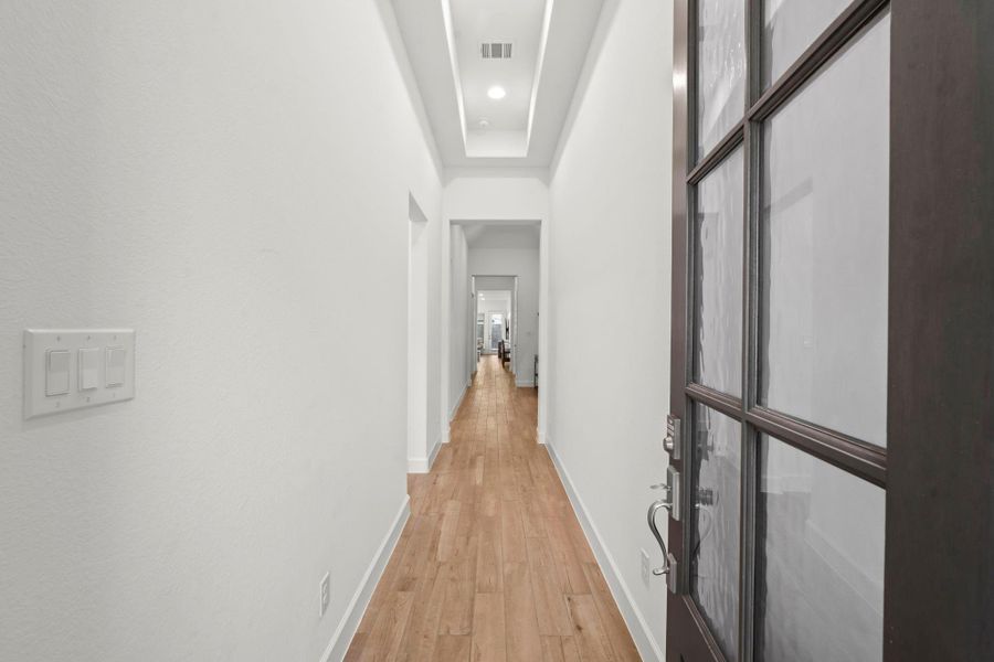 Step into sophisticated style with this stunning foyer, where every detail is designed to impress. Featuring wood-look tile flooring and a tray ceiling with classic recessed lighting, this space sets the tone for the warmth and elegance found throughout the home. With views all the way to the backyard, this entryway is as functional as it is beautiful—complete with a coat closet and space for an entry table or bench.