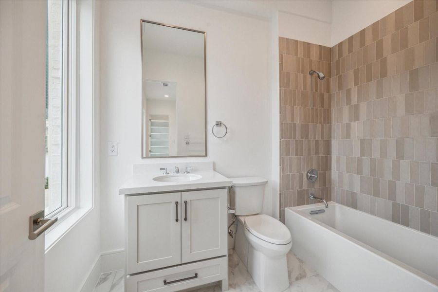 En-suite bath features Kohler Underscore alcove bath, Biancone Quartz countertops, and under-cabinet storage. En-suite bath features Kohler Underscore alcove bath, Biancone Quartz countertops, and under-cabinet storage.