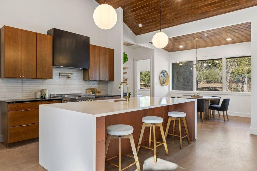 Kitchen featuring brown cabinetry, a breakfast bar, finished concrete floors, pendant lighting, and wooden ceiling
