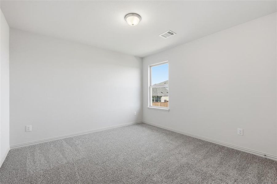 Bright room featuring neutral gray carpet, white painted walls, a single window, and a flush-mount ceiling light fixture