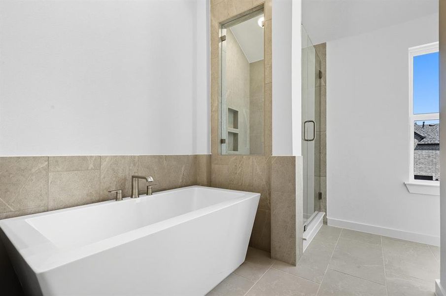 Full bath featuring a shower stall, a soaking tub, tile walls, and light tile patterned floors Full bath featuring a shower stall, a soaking tub, tile walls, and light tile patterned floors